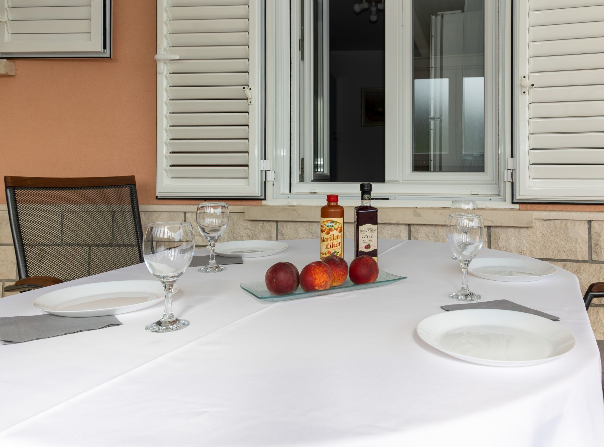 Un tavolo da pranzo apparecchiato con piatti, bicchieri e una bottiglia di Marillen Likon.