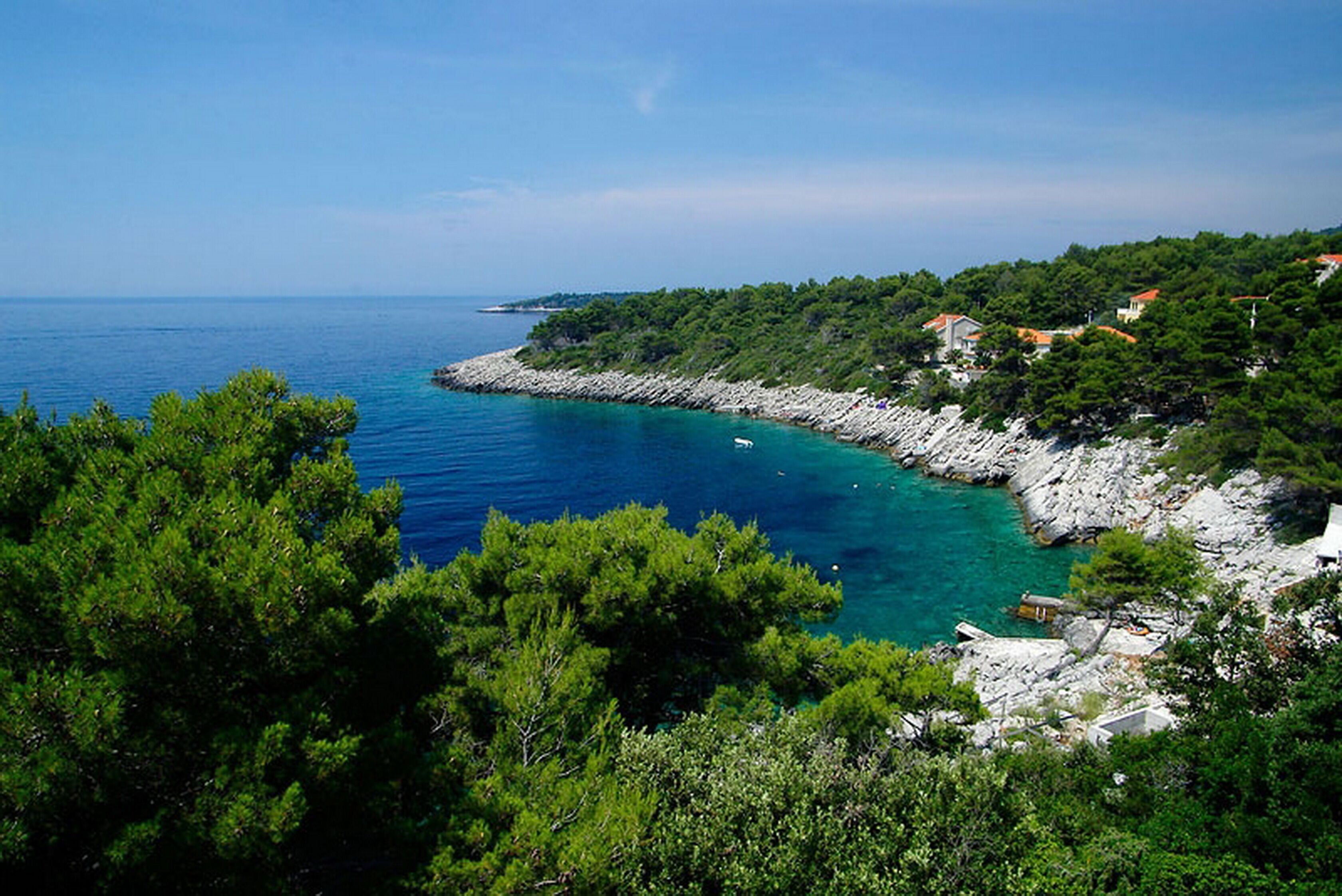Un paisaje costero con acantilados rocosos, abundante vegetación y mar azul cristalino.