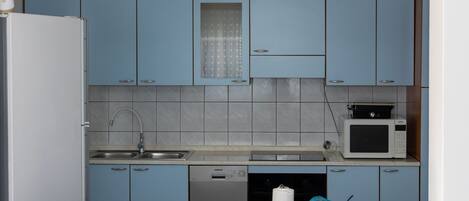 A compact kitchen with blue cabinets, a built-in microwave, and a dishwasher.