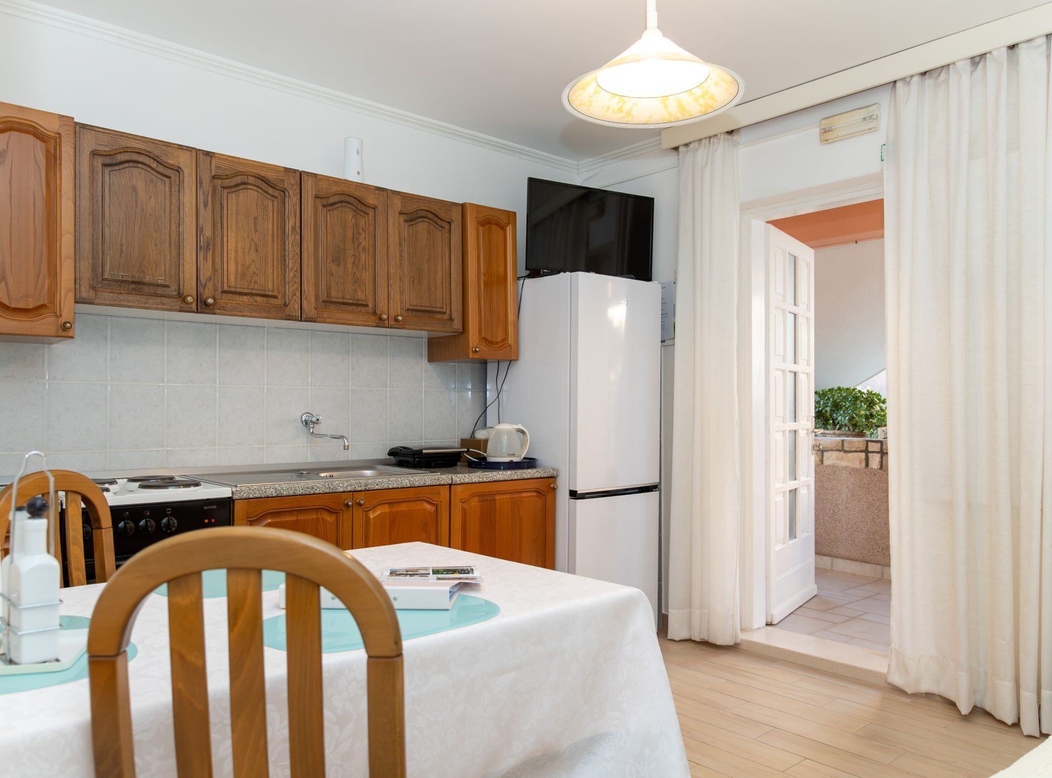 A modern kitchen with wooden cabinets, a white refrigerator, and a dining table with chairs.