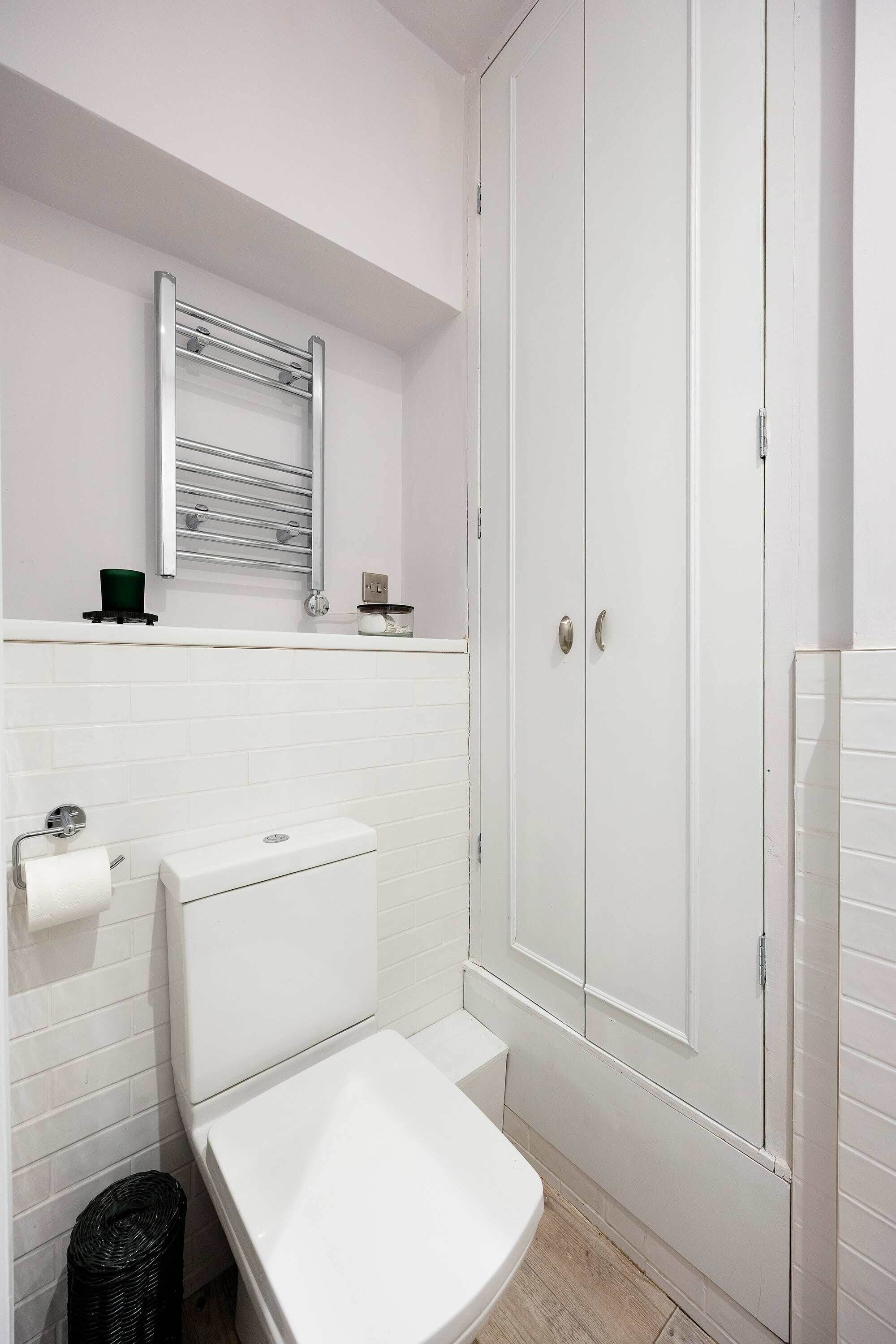 A bathroom with a toilet, a sink, a mirror, and a white cabinet.