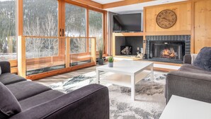 En moderne stue med pejs, store vinduer og et hyggeligt opholdsområde.