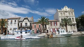 A marina with boats, a building with ornate architecture, and palm trees. - Studio for 4 people with terrace, near beach (Le Grau-du-Roi)