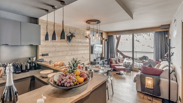 A modern kitchen with a wooden countertop, a fruit bowl, and a dining area with a sofa and a chair. - 4* Apartment Tignes 2 rooms, 4 people (Tignes)