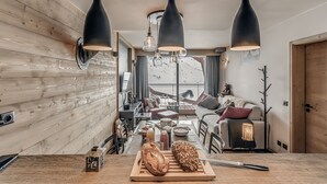 A modern kitchen with wooden accents, a dining area with a view of a snowy landscape, and a cozy living space with a sofa and a coat rack. - 4* Apartment Tignes 2 rooms, 4 people (Tignes)