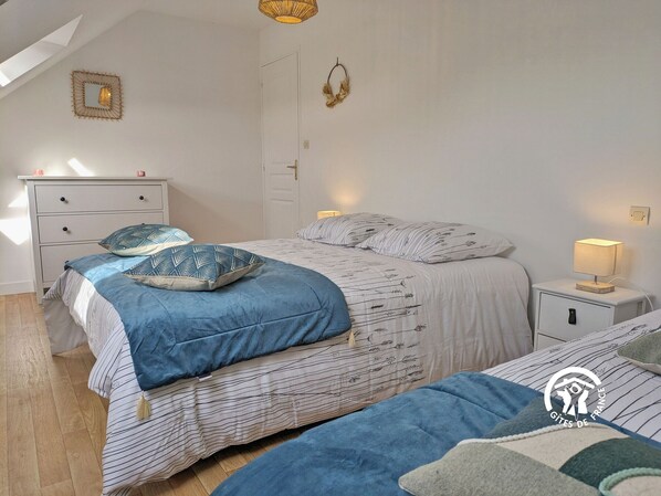 Een slaapkamer met twee bedden, een nachtkastje met een lamp, een kast en een spiegel aan de muur.
