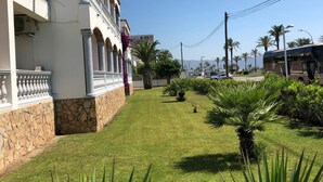 A building with a stone base and white upper structure, a well-maintained lawn, and palm trees.
