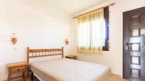 A bedroom with a wooden bed, bedside tables, a window with curtains, and a door.