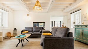 En moderne stue med en grå sofa, et træbord og en hængende lampe.