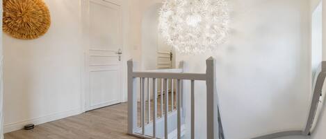 Un intérieur moderne avec un plancher en bois, une porte blanche et un luminaire sphérique original.