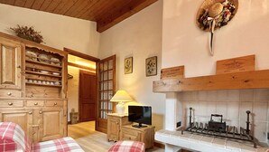 A cozy room with wooden furniture, a fireplace, and plaid cushions. - Charming 2-BR + Cabin, Sleeps 6, Close to Jaillet Gondola and Sports Palace - Megève (Megève)