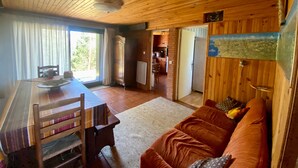 A wooden interior with a dining area, a sofa, and a kitchen.