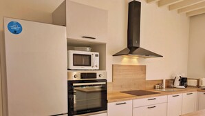 A modern kitchen with a built-in oven, microwave, and a range hood. - Comfortable country cottage - 6 guests (Mayenne)