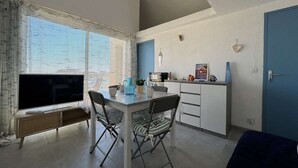 Ein kompakter Wohnbereich mit Essplatz, Küchenzeile und großem Fenster mit Ausblick.