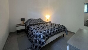 Ein Schlafzimmer mit einem Bett, einem Nachttisch mit Lampe und einem kleinen Fenster.