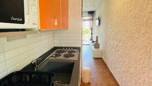 A kitchen with a stove, sink, and orange cabinets. - Seaside Studio with Terrace - 4 Guests, 1 Km to Beach, Parking Included (Lumio)
