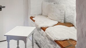 A corner of a room with a white bench, a small white table, and a textured wall. - 2 bedroom gorgeous home in Hamneda (Hamneda)