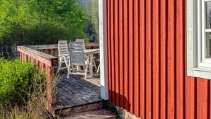 A red building with a wooden deck and outdoor seating. - 2 bedroom gorgeous home in Hamneda (Hamneda)