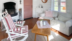 A cozy living room with a white rocking chair, a wooden coffee table, and a white sofa with pink pillows. - 2 bedroom gorgeous home in Hamneda (Hamneda)