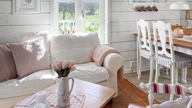 A cozy living room with a white sofa, a wooden coffee table, and a white dining table with chairs. - 2 bedroom gorgeous home in Hamneda (Hamneda)