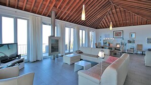Un salon spacieux avec un haut plafond, une cheminée et de grandes fenêtres.