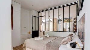 Un dormitorio moderno con una cama grande, un armario y vistas a la ciudad a través de amplias ventanas.