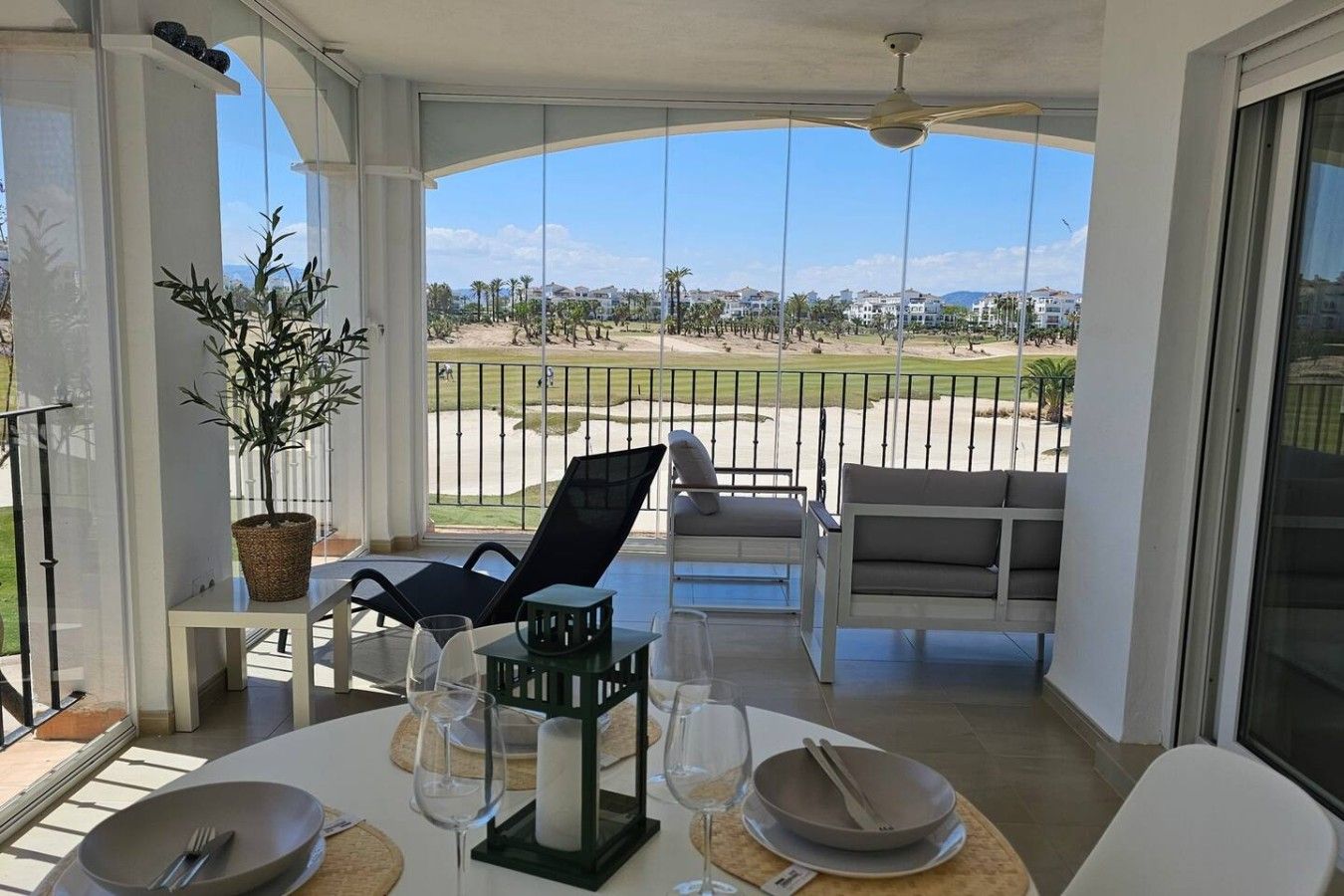 A balcony with a dining setup, including chairs, a table, and a potted plant.