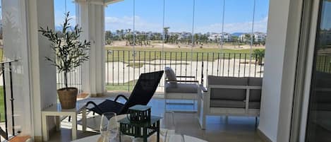 A balcony with a dining setup, including chairs, a table, and a potted plant.