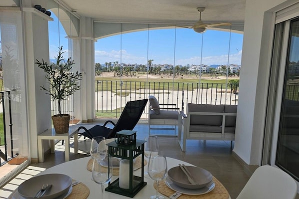 A balcony with a dining setup, including chairs, a table, and a potted plant.