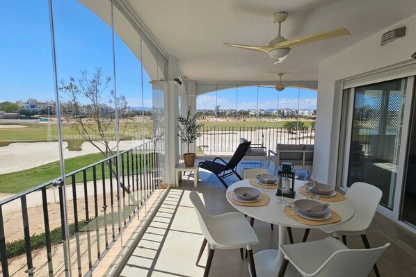 A balcony with a dining table set for four, overlooking a golf course.