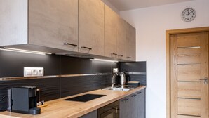 Eine moderne Küche mit dunklen Schränken, einer Holzarbeitsplatte und einem eingebauten Backofen.