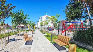 A paved walkway with benches and a playground area.