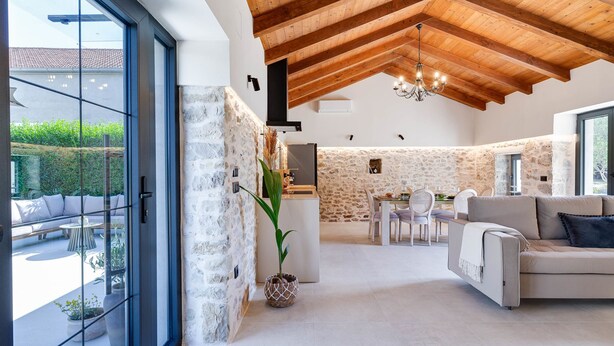 Un espacio habitable amplio con una pared de piedra, una mesa de comedor y un sofá.