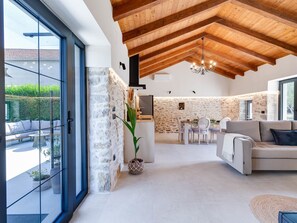A spacious living area with a stone wall, a dining table, and a sofa.