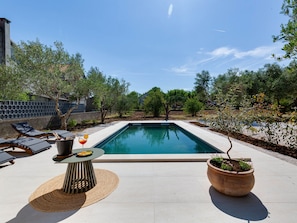 Relax by the serene pool surrounded by lush greenery and comfortable seating.