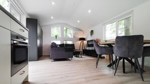 A modern kitchen with built-in appliances, a dining area with a table and chairs, and large windows allowing natural light. - Lovely home in Hellendoorn with WiFi (Hellendoorn)