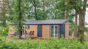 A small wooden cabin with a metal roof, surrounded by trees and greenery. - Lovely home in Hellendoorn with WiFi (Hellendoorn)
