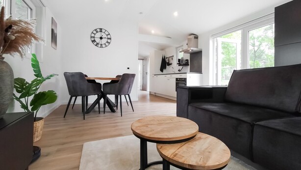 A modern living room with a dining area, a black sofa, and a round wooden coffee table. - Lovely home in Hellendoorn with WiFi (Hellendoorn)