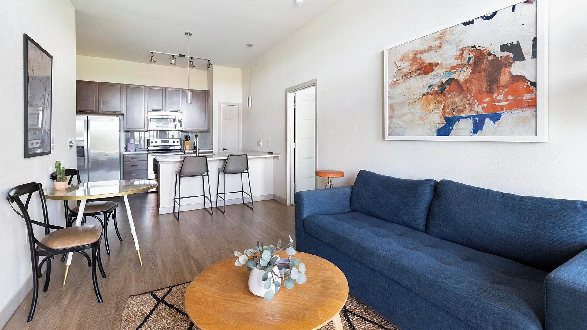 A modern apartment with a living room, dining area, and kitchen.