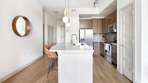 A modern kitchen with a central island, stainless steel appliances, and wooden cabinets.
