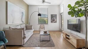 A modern living room with a sofa, a coffee table, a TV, and a plant.