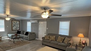 A living room with a ceiling fan, a sofa, a coffee table, and a lamp.
