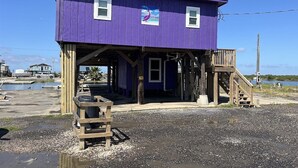 A purple building with a wooden deck and a staircase.