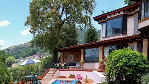A house with a swimming pool, patio furniture, and a view of the surrounding landscape.