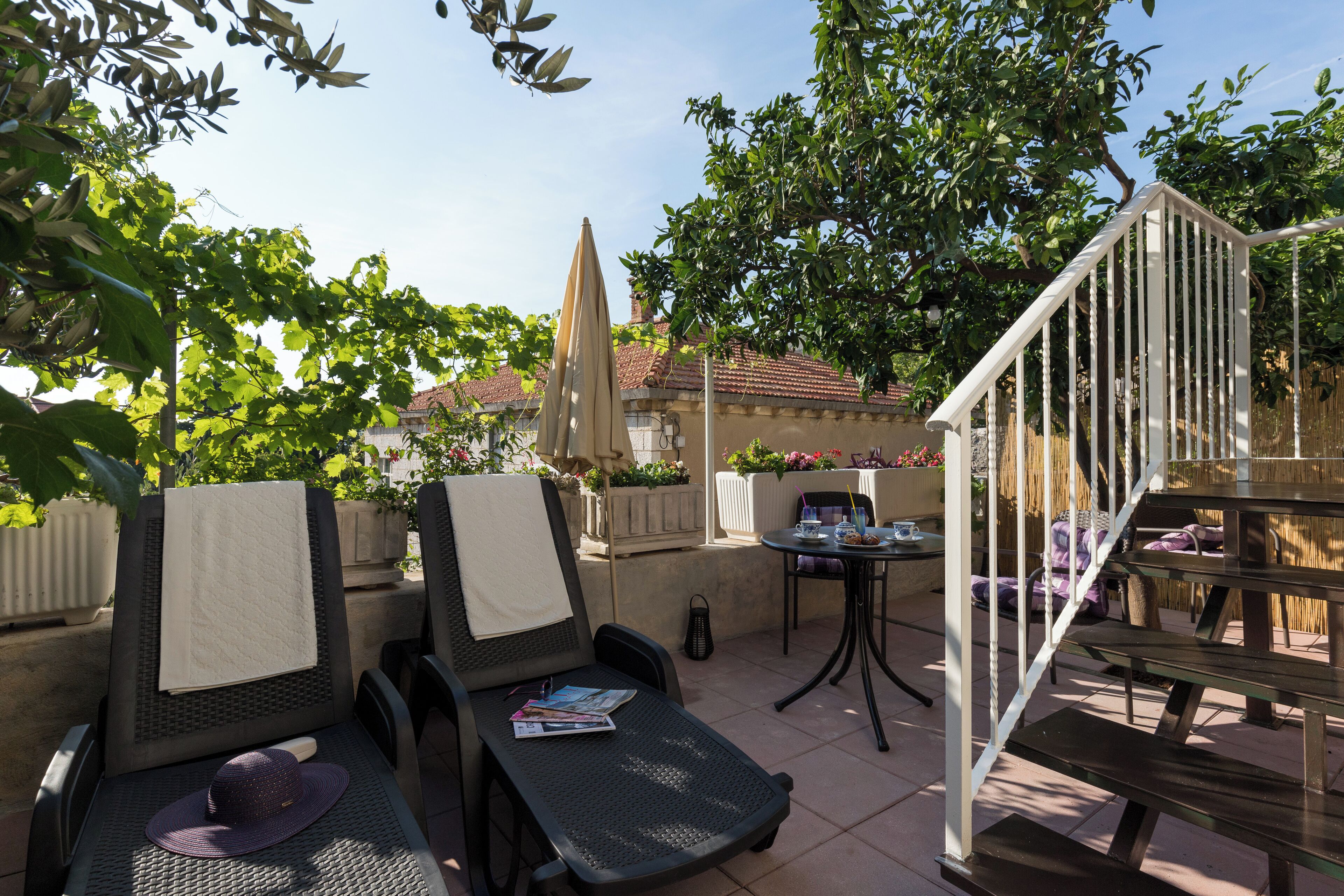 Patio esterno con due poltrone, un tavolo e una scalinata.