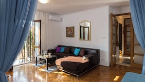 A modern living room with a sofa, a coffee table, and a dining area. - Apartment Vukic (Dubrovnik)