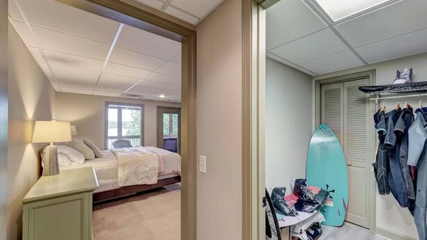 A bedroom with a bed, a nightstand, a surfboard, and a closet with hanging clothes. - Cozy 3BR Cabin with Lake View in Dawsonville (Dawsonville)