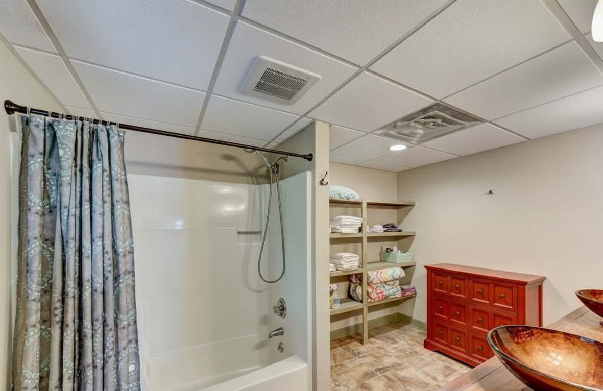 Un baño con ducha, lavamanos y repisas con toallas dobladas.