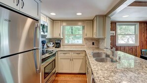 A modern kitchen with stainless steel appliances, granite countertops, and wooden cabinetry. - Cozy 3BR Cabin with Lake View in Dawsonville (Dawsonville)