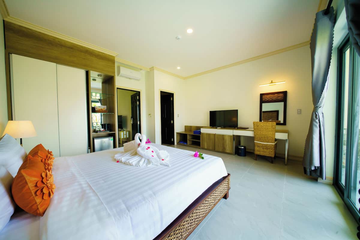 A hotel room with a large bed, a desk, a television, and a bathroom.